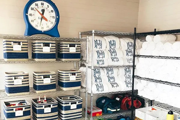 Storage room with shelves containing baskets, bags, and a clock on the wall.